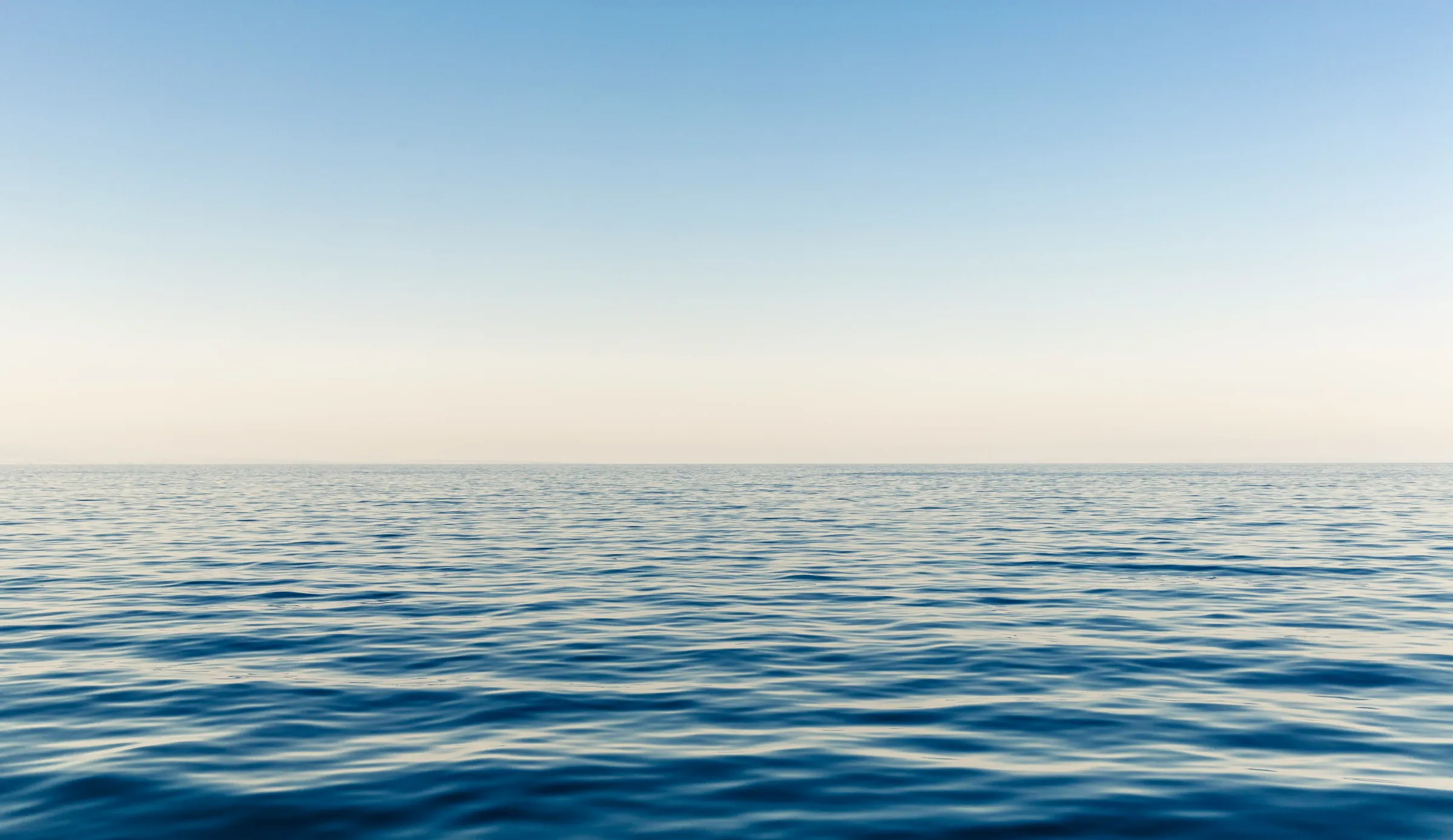 Calm open water beneath a soft, clear sky