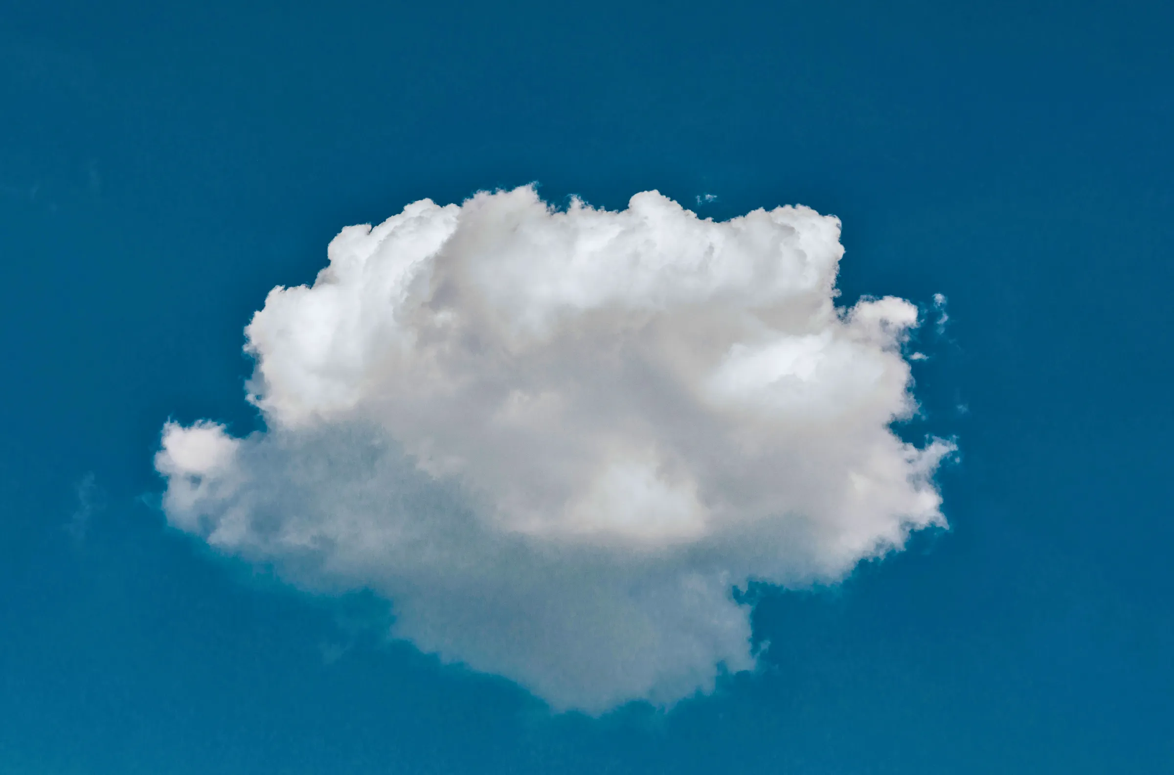 A single white cloud floating in a vivid blue sky